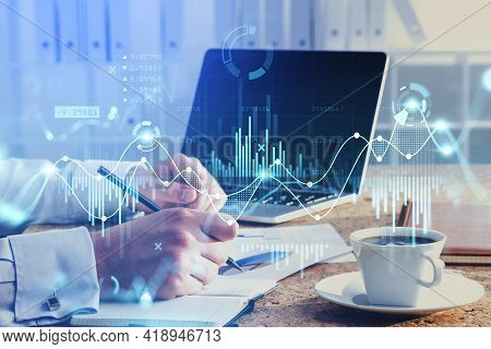 Office Man Hand With Pen And Business Papers, Laptop On The Table With Cup Of Coffee. Graph Changes,