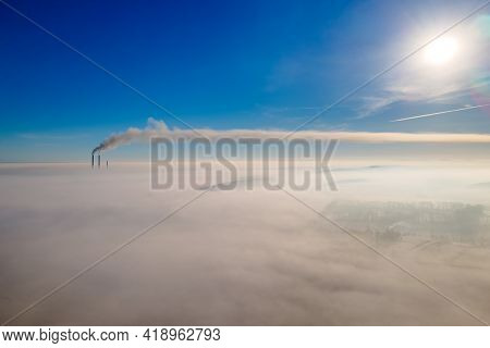 Aerial View Of Winter Landscape With Foggy Countryside And Distant Factory Pipes Emmiting Black Dirt