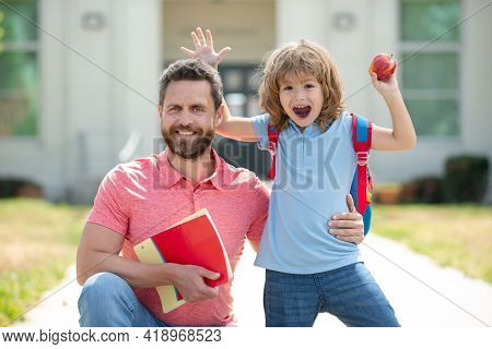 Happy Family At School Yard. Teacher In T-shirt And Cute Schoolboy With Backpack Near School Park. F