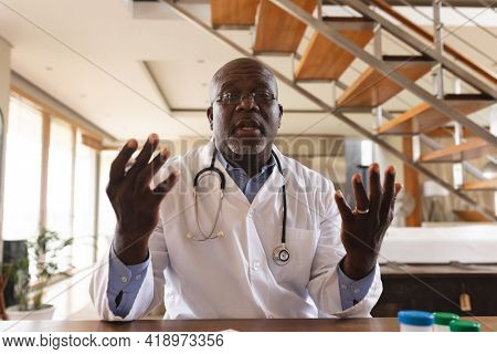 Portrait of african american senior male doctor talking looking at the camera at home. distant communication and telemedicine consultation concept.
