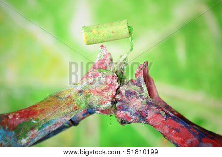 Two pairs of hands all in the paint keep the roller and doing the thumbs up