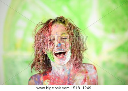 Face laughing girl covered in paint with closed eyes 