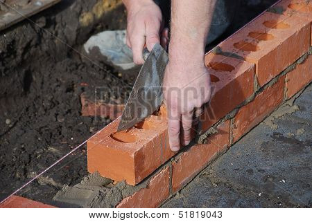 Bricklayer using trowel to tap a brick level