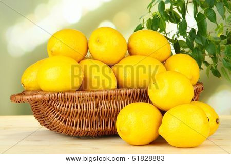 Ripe lemons in wicker basket on table on bright background