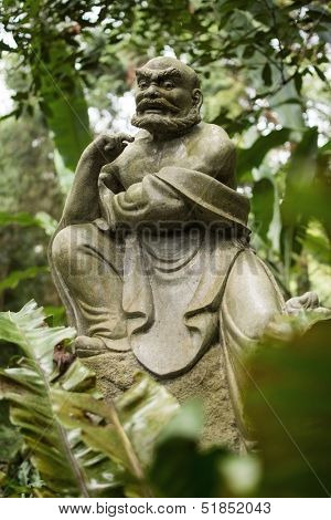 Old ruined Arhat Kanakbharadvaja statue in forest, Taiwan, Asia.
