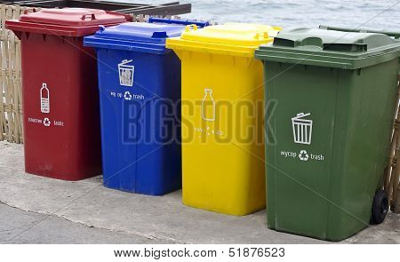 Four Color Trash Cans In The Park Beside The Walk Way.