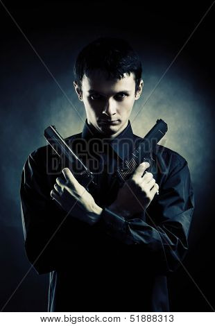 Killer with two pistols on dark background