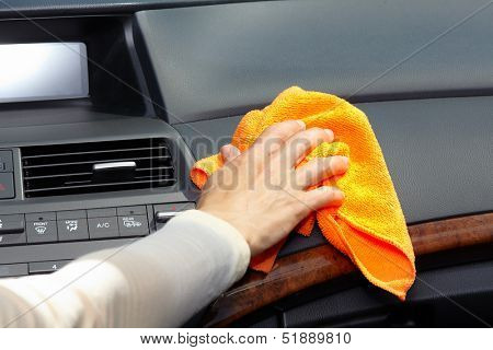 Hand with microfiber cloth cleaning car.