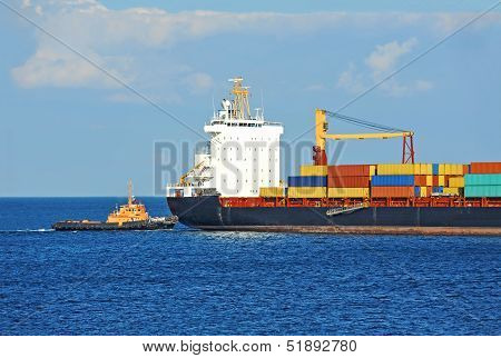 Tugboat assisting container cargo ship