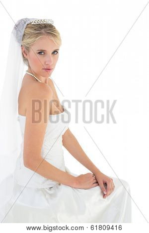 Portrait of sensuous bride in off shoulder dress sitting against white background