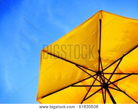 Yellow umbrella and blue sky symbolizing vacationing in summer