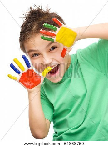 Portrait of a cute cheerful boy showing her hands painted in bright colors, isolated over white