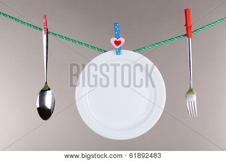 Tableware dried on rope on grey background