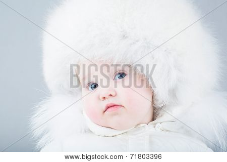 Very Funny Baby In A White Snow Suit And Big Fur Hat