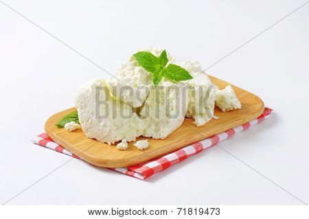 slices of fresh cheese on wooden cutting board and checkered dishtowel
