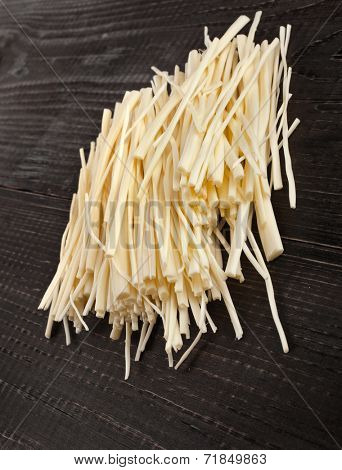 rennet cheese spaghetti heap on wooden table close up