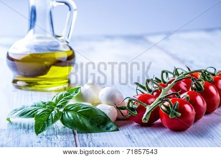 Cherry tomatoes, basil leaves, mozzarella cheese and olive oil for caprese salad.