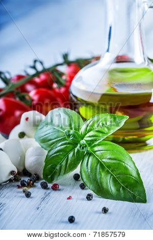 Cherry tomatoes, basil leaves, mozzarella cheese and olive oil for caprese salad.