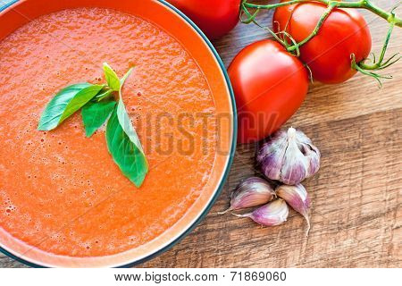 A bowl of tomato soup gaspacho with basil, tomatoes and garlic