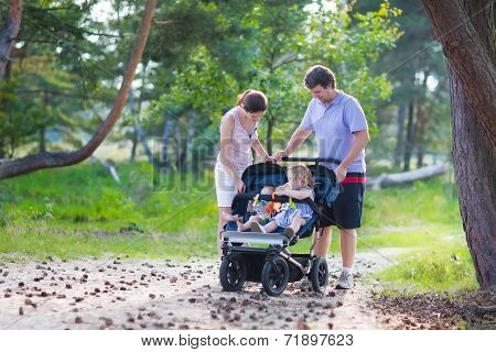 Young Family Hiking With Two Kids In A Stroller
