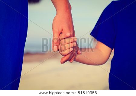 mother and son holding hands on the beach