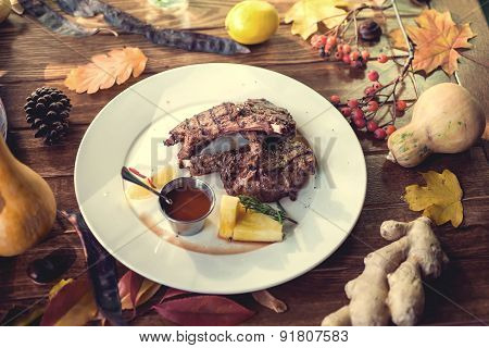 Close up of grilled pork ribs with lemon, sauce and rosmary. Selective Focus. Autumn concept decorat