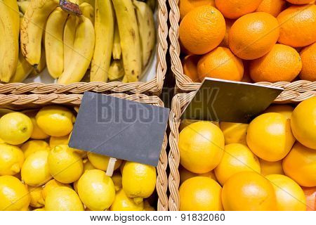 sale, shopping, vitamin c and eco food concept - ripe fruits in baskets with nameplates at grocery market