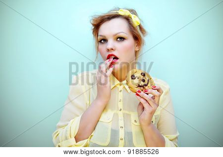 Trendy young woman is eating a smiling chocolate chip cookie.