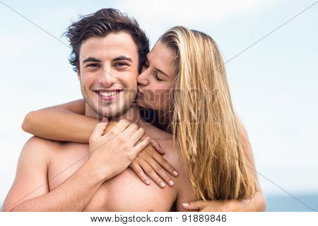 Handsome man receiving kiss from his gilfriend at the beach