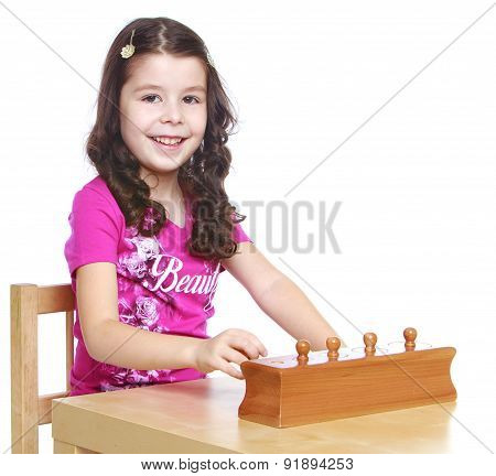 Smart girl  sitting at the table  learning Montessori material