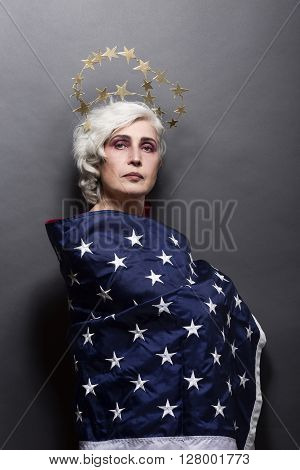 Portrait of mature fashion or vogue woman posing for American magazine over gey background in studio. USA flag concept.
