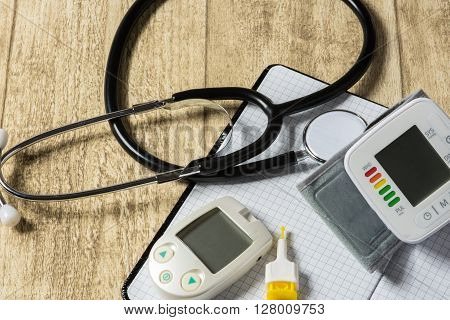 Stethoskope on wooden desk with blood pressure measurement