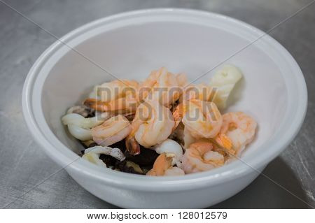 Fresh grilled shrimps with lemon on a pot of soup.