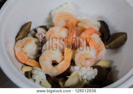 Fresh grilled shrimps with lemon on a pot of soup.