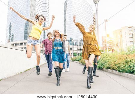 Group of happy friends walking and having fun in an urban area - Multi-ethnic group of young people jumping and dancing outdoors