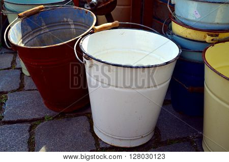 old, different colored buckets standing at the street