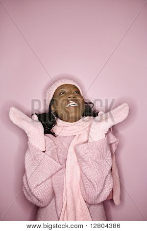 Portræt af smilende afrikansk-amerikanske mid-adult kvinde på pink baggrund iført vinter jakke, hat, en