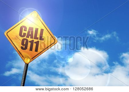 Yellow road sign with a blue sky and white clouds: call 911