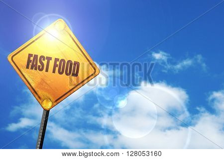Yellow road sign with a blue sky and white clouds: Delicious fas