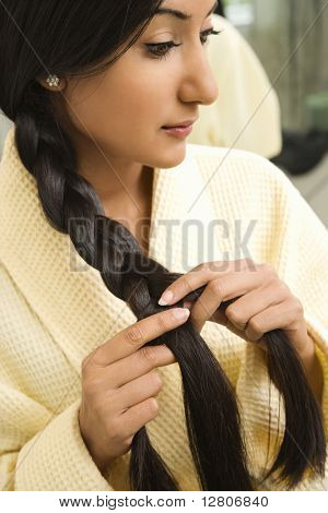 Feche o perfil de jovem mulher asiática/indiano, trançar cabelo.