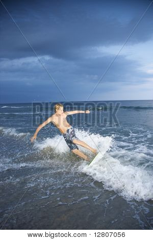 Kavkazská muž teen jízdy skimboard.