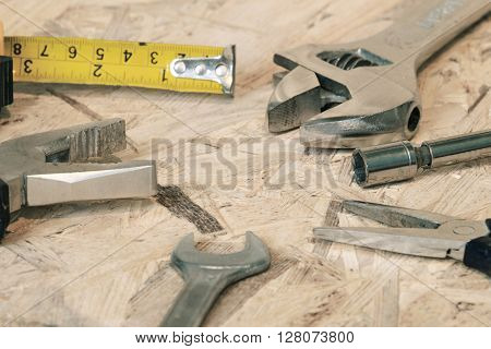The working tools for construction and repair of house: tape measure (yardstick), wrench, screwdriver, pliers, spanner, screw. Photos with limited depth of field.