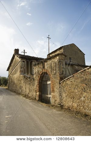 Vecchia pietra buillding in stato di abbandono con ingresso ad arco gated in Toscana.