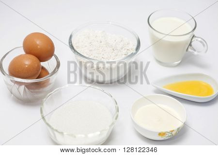Ingredients to prepare crepes on white background