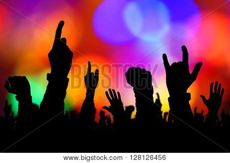 Silhouettes of concert crowd hands supporting band performing live music on stage young people on rock gig enjoying.