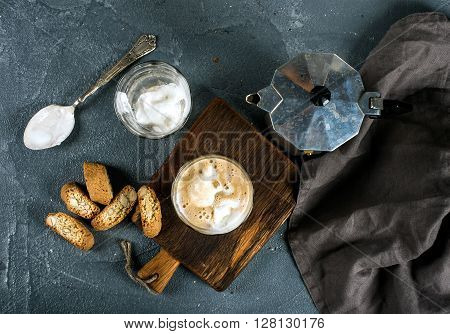 Glasses of coffee with ice cream on rustic wooden board, steel Italian Moka pot over grey concrete textured background, top view, horizontal