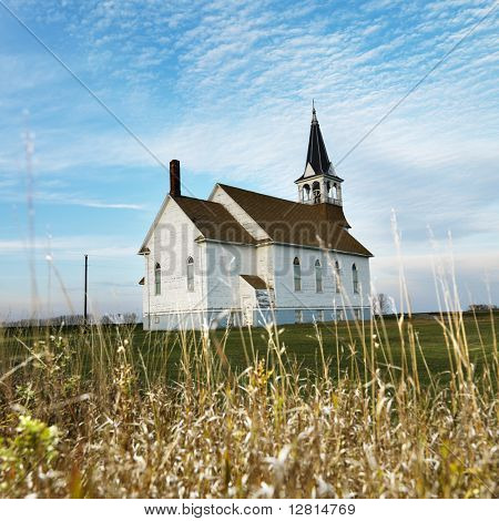 Small rural church in field with chipped wood siding.