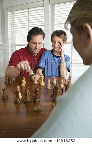 Indoeuropea madre males males papà insegnare gli scacchi al figlio pre-adolescente a guardare.