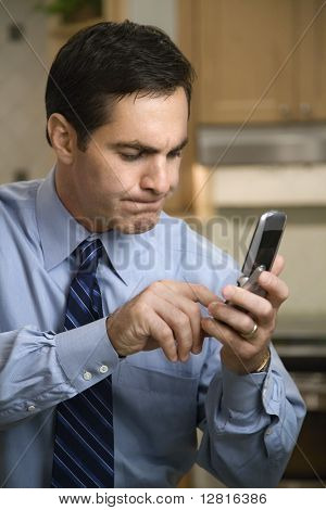 Mid kaukasischen Männchen Handy Tasten stehen in der Küche.