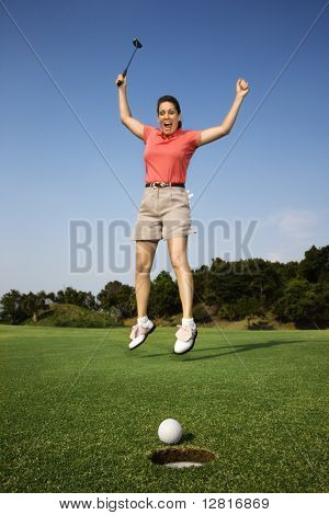 Lüneburg adult Woman holding Golf Club springen in der Luft jubeln mit Golfball und Loch in foreg